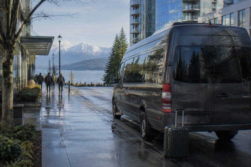 A tour van parked on a downtown Seattle street beside hotels in morning light